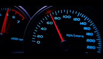 A close up of a speed odometer showing 0 to 220. Instead of reading kilometres it reads age/years. The dial is sitting on 65.