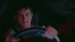 A man is behind the wheel of a speeding car at night.